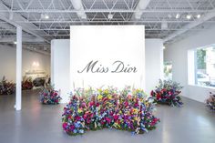 a room filled with lots of colorful flowers on the floor and a sign that says miss dior