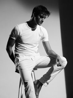 black and white photograph of a man sitting on a chair with his hands in his pockets