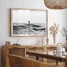 a dining room table with chairs and a painting on the wall above it, along with wicker furniture