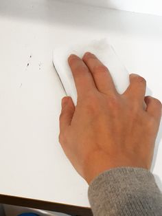 a person's hand on a computer mouse near a white surface with holes in it