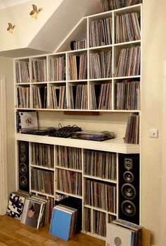 an entertainment center filled with lots of records and audio cassettes on top of bookshelves