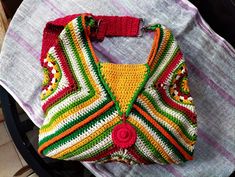 a crocheted purse sitting on top of a chair next to a table with a white cloth