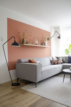 a living room with a couch, table and lamp on the wall in front of it