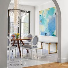 a dining room with an archway leading to the kitchen and living room, along with a painting on the wall