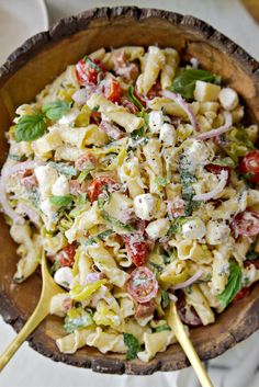 a wooden bowl filled with pasta salad on top of a table