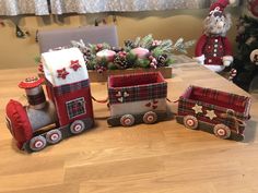 a wooden table topped with christmas decorations next to a toy train and santa's sleigh