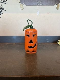 an orange pumpkin shaped container sitting on top of a wooden table next to a wall