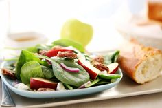 a white plate topped with salad next to a slice of bread