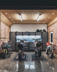 two motorcycles are parked in a garage with lights on the ceiling and one is empty