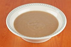 a white bowl filled with soup on top of a wooden table