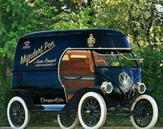 an old fashioned car is parked in front of some trees