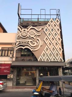 a man riding a scooter in front of a building with an intricate design on it