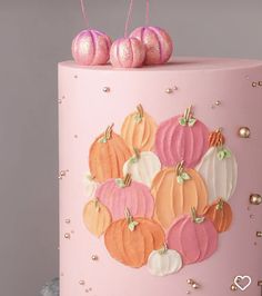 a pink cake decorated with pumpkins and glitter decorations on it's top,