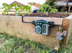 a meter attached to the side of a wooden planter box with plants growing in it