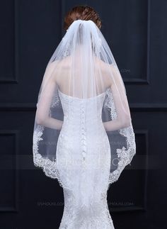 a woman in a wedding dress with a veil on her head is looking back at the camera