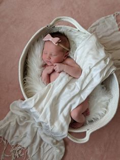 a baby wrapped in a white blanket laying on top of a bed