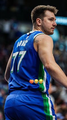 a male basketball player in a blue uniform is holding a ball and looking at the crowd