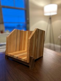 a small wooden object sitting on top of a table next to a lamp and window