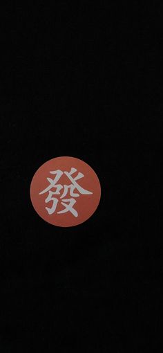 a red and white sticker with chinese writing in the middle on a black background