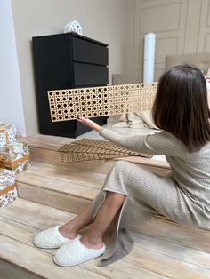 a woman sitting on top of a wooden floor next to a piece of wood cut out