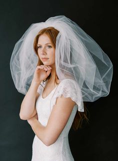 a woman with a veil on her head is posing for a photo in front of a black background