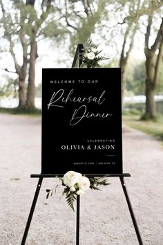 a welcome sign with flowers on it in the middle of a park setting for an outdoor wedding