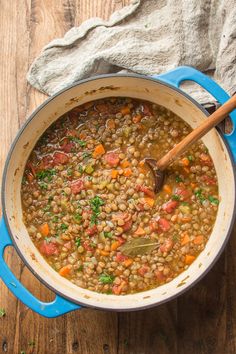 a blue pot filled with beans and carrots on top of a wooden table next to a