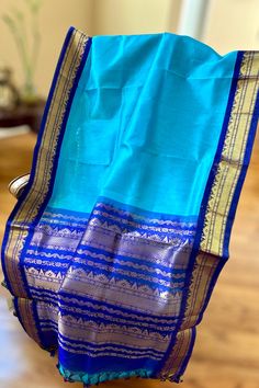 This regal korvai silk cotton saree in rama blue with ink blue border and pallu is handwoven. The saree borders are adorned with traditional motifs in gold zari. The ink blue pallu is grand with a rich gold zari work. Approximate Length 6.5 mtrs (inclusive of blouse length) Approximate weight - 1.2 lbs Approximate Height - 48 - 50" Saree comes with fall, picot and tassels done when applicable. Blouse piece is cut. Kindly Note : The colors you see on your device may vary due to the color reproduction, brightness and resolution of individual devices. If you'd like more clarity before your purchase, please contact our support team. Blue Slub Silk Traditional Bollywood Wear, Blue Saree With Printed Border, Blue Katan Silk Dupatta With Printed Border, Blue Banarasi Silk Traditional Wear With Printed Border, Blue Saree With Printed Border For Festivals, Blue Tussar Silk Dupatta With Printed Border, Blue Chanderi Dupatta With Printed Border, Blue Slub Silk Saree For Festivals, Festive Blue Dupatta With Printed Border