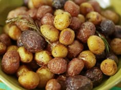 a green bowl filled with lots of different types of nuts on top of a table