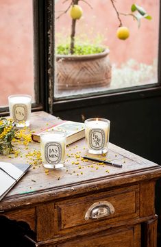 two candles sitting on top of a table next to an open book and some flowers