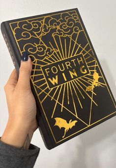 a person holding up a black and gold book