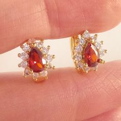 These Beautiful Red Topaz Hoop Huggie Earrings Are Made Of 18k Yellow Gold Filled. The Red Pear Shape (Lab Created) Topaz Zircon Stones Are 4mm X 6mm And Are Surrounded By Smaller White Topaz Stones. Brand New And Never Been Worn. Lead And Nickel Free. These Fine Quality Earrings Are Perfect And Comfortable For Special Occasions Or A Special Gift. Please Send Offers And Questions. Big Stone :4 X 6mm Or 16" X .24" Earrings: .35"X .39" Hoop: .47" Hoop Clasp: Pierced Red Gemstone Gold-plated Earrings, Red Gemstone Gold Plated Earrings, Red Cubic Zirconia Earrings For Gift, Red Birthstone Drop Earrings, Red Cubic Zirconia Birthstone Earrings, Red Clip-on Jewelry For Anniversary, Stone Earrings Studs, Red Topaz, Red Pear