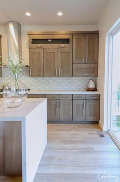 a large kitchen with wooden cabinets and marble counter tops, along with glass vases on the island