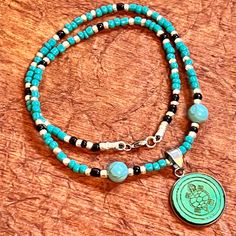 This stunning Native American-style necklace is a beautiful piece of jewelry that will add a touch of elegance to any outfit. The handcrafted glass seed  beads in hematite turquoise are strung together to create a unique and colorful design that is sure to catch the eye. The round pendant is engraved with a wood design, adding a touch of sophistication to the piece.  The lobster closure ensures that the necklace stays securely in place, while the 20-inch length makes it perfect for layering with Turquoise And Black Beads Necklace For Jewelry Making, Spiritual Hematite Necklace With Black Beads, Turquoise Symbolic Adjustable Jewelry, Adjustable Beaded Turquoise Necklace For Meditation, Spiritual Turquoise Crystal Necklace With Polished Beads, Turquoise Jewelry With Black Beads For Gift, Hematite Beads For Gifts, Turquoise Pendant Beaded Necklace With Adjustable Fit, Spiritual Turquoise Beaded Adjustable Necklace