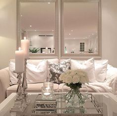 a living room filled with white furniture and candles on top of it's coffee table