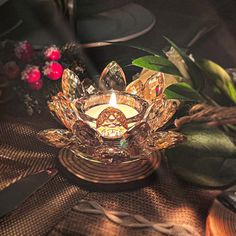 a lit candle sits on top of a table with flowers and other items around it