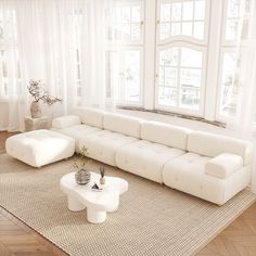 a large white couch sitting on top of a rug in a living room next to a window