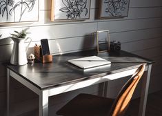 a desk with a laptop computer on top of it next to a vase and other items