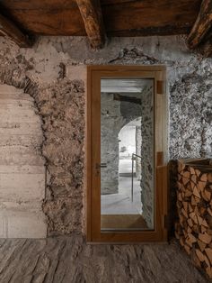 an old stone building with wood stacked on the floor and a mirror in front of it