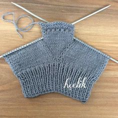 a knitted sweater with the word keesh written on it and knitting needles next to it