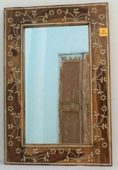 an old wooden mirror with white flowers on the border and a blue sky in the background