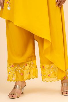 Turmeric yellow asymmetric kurta with flower vine embroidery. Paired with a pant with scallop trimmed hemline and floral embroidery.
Components: 2
Pattern: Placement Hand Embroidery
Type Of Work: Floral
Neckline: Collared Neck
Sleeve Type: Three Quarter Sleeves
Fabric: Morrocan Crepe
Color: Yellow
Other Details: 
Organza detailed sleeves
Side pockets on pant
Occasion: Sangeet - Aza Fashions Flower Vine Embroidery, Vine Embroidery, Asymmetric Kurta, Turmeric Yellow, Pant For Women, Kurta With Pants, Flowering Vines, Three Quarter Sleeves, Quarter Sleeve