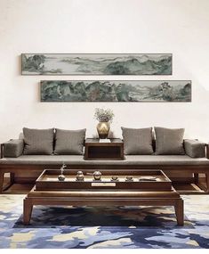 a living room with couches, coffee table and paintings on the wall above it