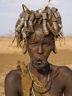 an african woman with metal hair clips on her head and necklaces around her neck