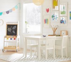 a child's room with white furniture and pictures on the wall, including a chalkboard