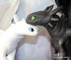 two toy dragon figurines one is black and the other is white with green eyes