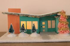 a small green house with trees and snow on the ground