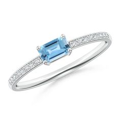 In the middle of a sleek diamond encrusted band is an emerald cut Blue Topaz mounted horizontally. The diamonds are embellished in a pavé setting and splendidly complement the vividness of the blue center stone. This elegant east west Blue Topaz ring in 14K white gold has an enticingly understated charm. Blue Diamond Ring With Baguette Diamonds, Blue Emerald Cut Diamond Ring With Diamond Accents, Blue Emerald Cut Diamond Ring With Accents, Blue Diamond Ring With Diamond Accents Emerald Cut, Blue Emerald Cut Diamond Ring With Accent Stones, Emerald Cut Topaz Promise Ring With Diamond Accents, Emerald Cut Topaz Ring With Diamond Accents For Promise, Blue Topaz Diamond Ring With Emerald Cut, Blue Emerald-cut Topaz Ring With Diamond Accents