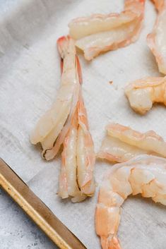 raw shrimp being prepared on a sheet of parchment paper with a knife next to it