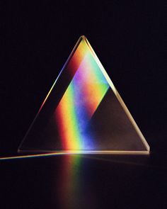 a triangle shaped object with rainbow light coming from it